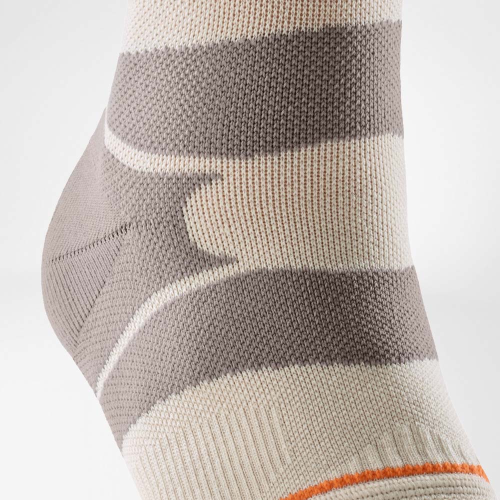 Vista dettagliata della Outdoor Compression Ankle Support nel colore sandstone. L’immagine mette in evidenza la zona di stabilizzazione laterale e la struttura a maglia che supporta la caviglia durante le escursioni su terreni irregolari.