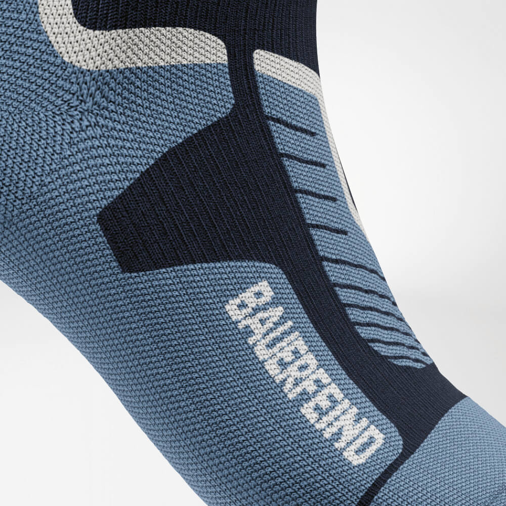 Primo piano del collo del piede di un calzino a compressione da sci blu con motivo a maglia rinforzato per un supporto ottimale e una distribuzione della pressione uniforme. Perfetto per lunghe giornate sulle piste.