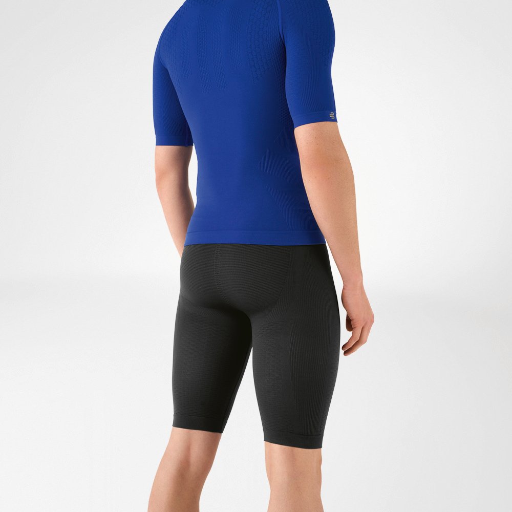 L'uomo indossa una camicia blu aderente che mette in risalto la parte superiore del corpo e pantaloni sportivi aderenti blu navy lunghi fino al ginocchio che abbracciano la parte inferiore del corpo.