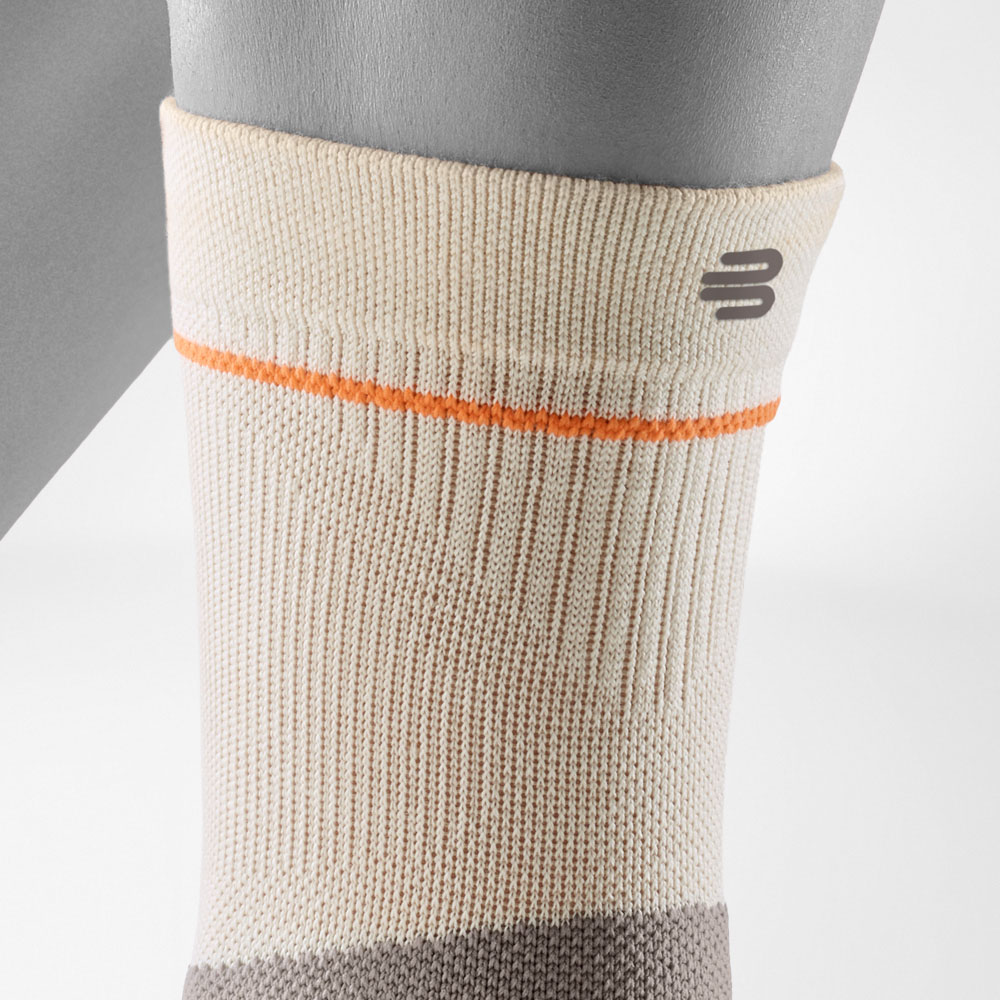Dettaglio della parte superiore della Outdoor Compression Ankle Support in colore sandstone. La struttura a coste, la vestibilità aderente e il logo Bauerfeind Sports garantiscono stabilità anche durante escursioni prolungate.