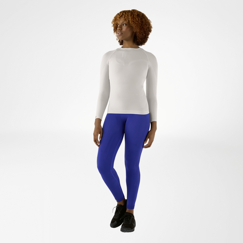 Donna con maglia a maniche lunghe grigio argento aderente e pantaloni a compressione blu, vista frontale
