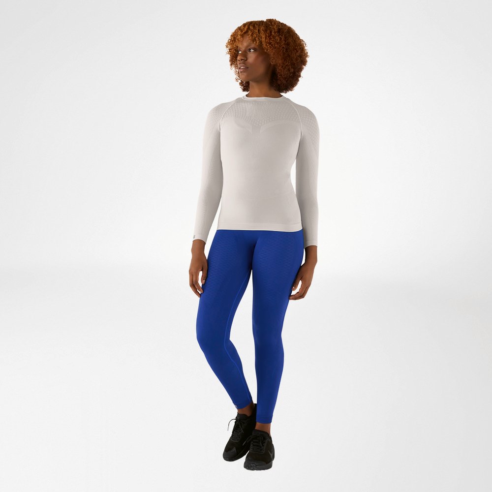 Donna con maglia a maniche lunghe grigio argento aderente e pantaloni a compressione blu, vista frontale