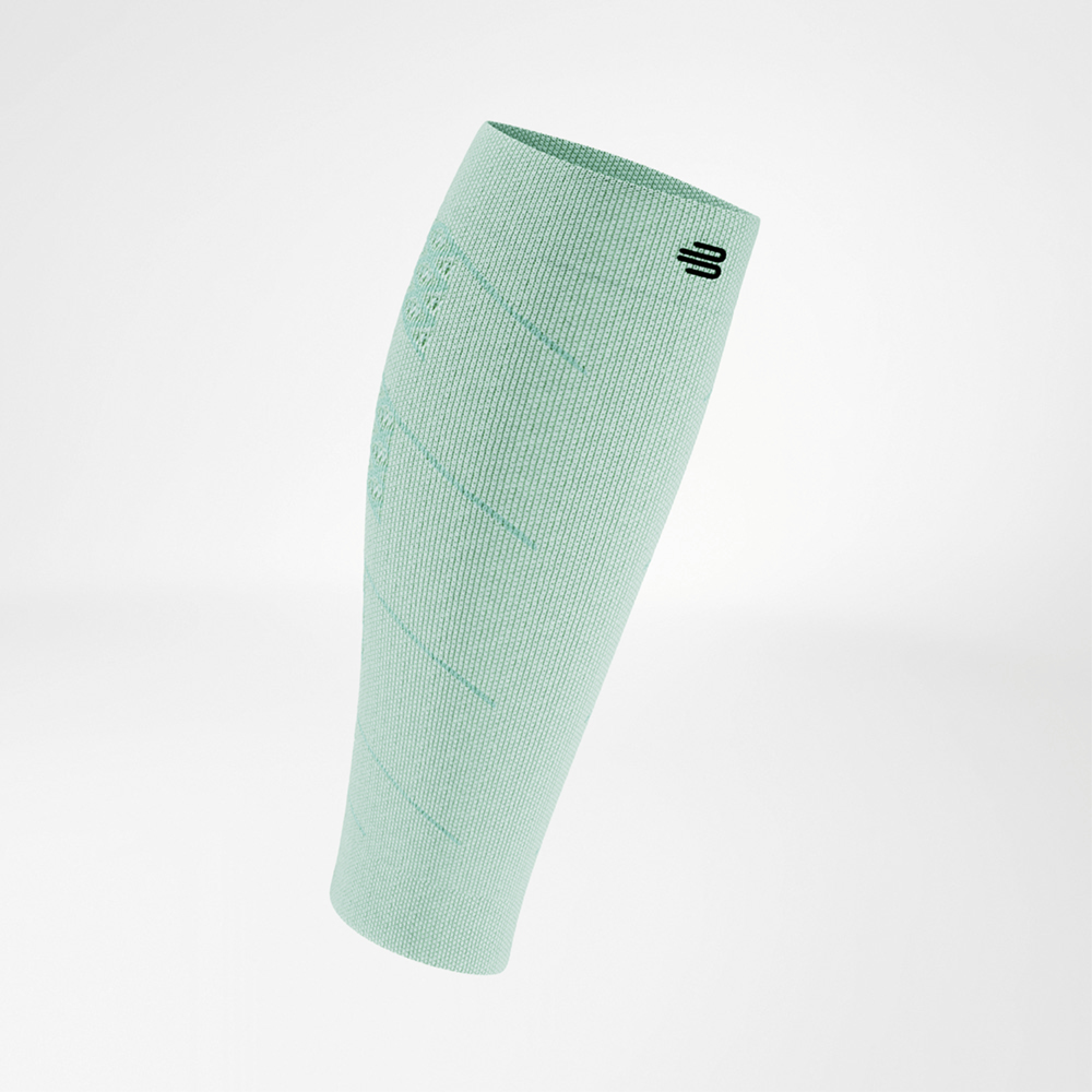 Sleeve a compressione verde chiaro in vista laterale inclinata, con logo nero in alto. Il tessuto leggero e traspirante avvolge il polpaccio con delicate strutture a maglia.