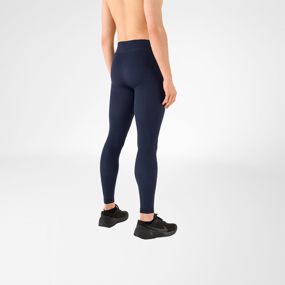È possibile vedere un dettaglio di un uomo a torso nudo che indossa scarpe sportive nere e pantaloni a compressione grigio antracite. È in piedi di lato e dà le spalle alla telecamera.