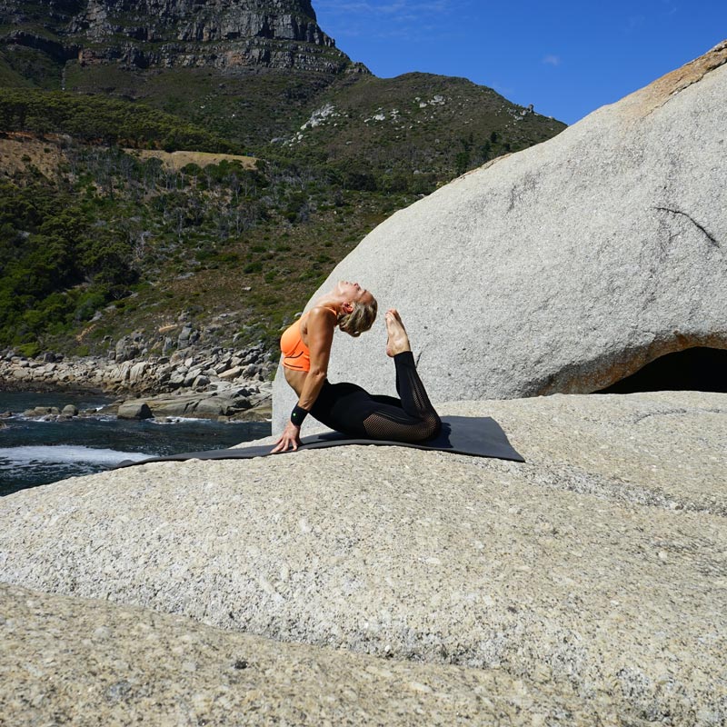 Yoga all'aperto - cinghia da polso sportivo nero La donna nella posa di Königskobra nella cavità si incrocia la testa tocca le punte della punta