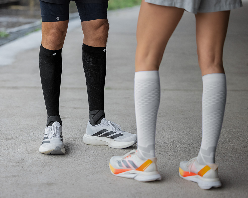 In pieno splendore: i nostri calzini a compressione per prestazioni run nel tuo elemento La parte inferiore della gamba di un corridore in ravvicinata con calzini in esecuzione a motivi blu su una superficie di cemento