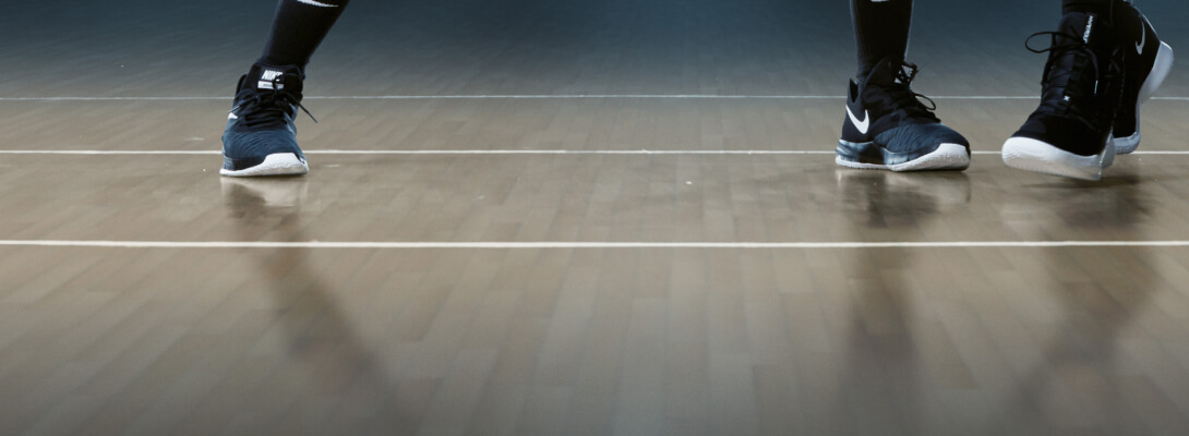 Vista del pavimento di una sala da basket e dei piedi di due giocatori