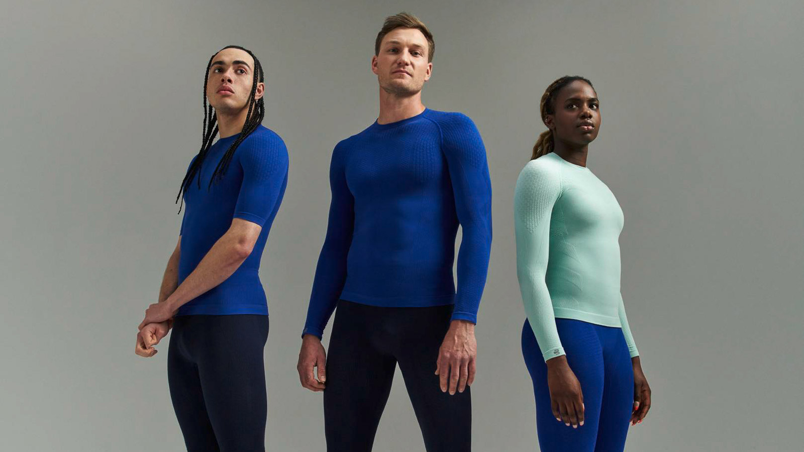 Tre atleti in abbigliamento sportivo con maglie a compressione e pantaloni a compressione Tre atleti in abbigliamento sportivo con maglie a compressione e pantaloni a compressione davanti a uno sfondo grigio.