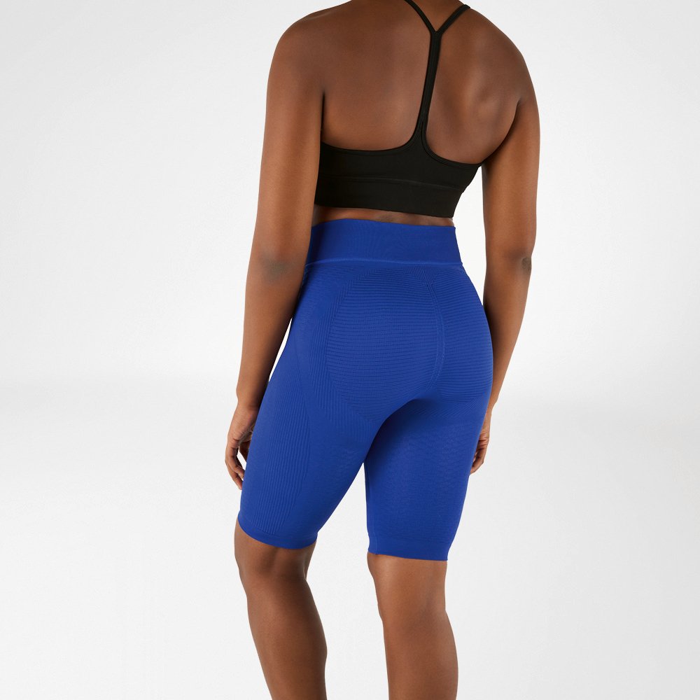 Donna fotografata da dietro con reggiseno sportivo nero e leggings compressivi blu al ginocchio.