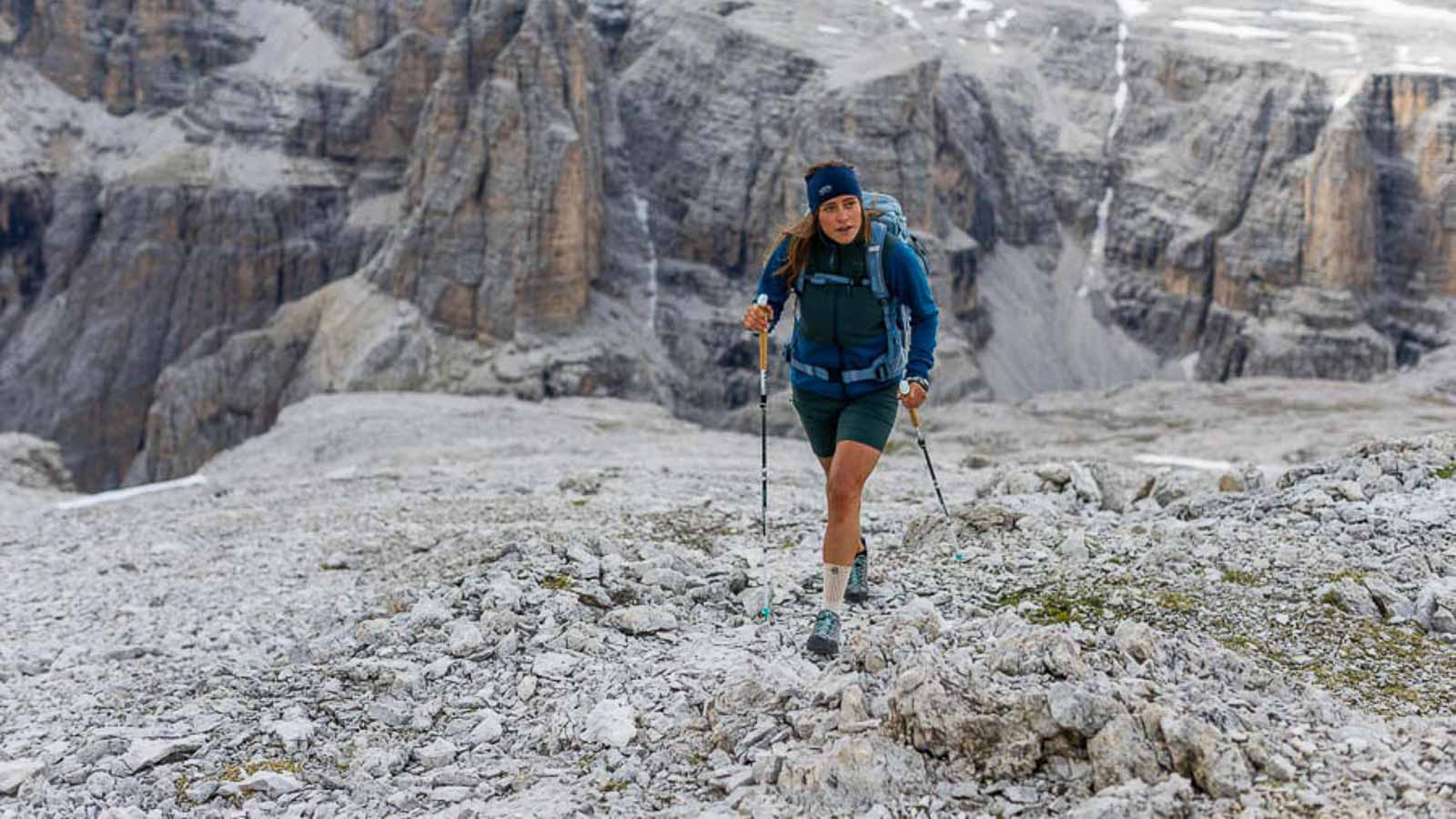 Un'escursione impegnativa ma bellissima nelle Dolomiti Una escursionista nelle Dolomiti cammina con dei bastoncini su un campo roccioso e indossa una fasciatura da trekking.