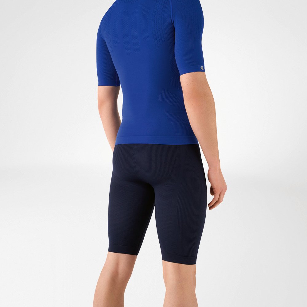L'uomo indossa una camicia blu aderente che mette in risalto la parte superiore del corpo e pantaloni sportivi aderenti blu navy lunghi fino al ginocchio che abbracciano la parte inferiore del corpo.