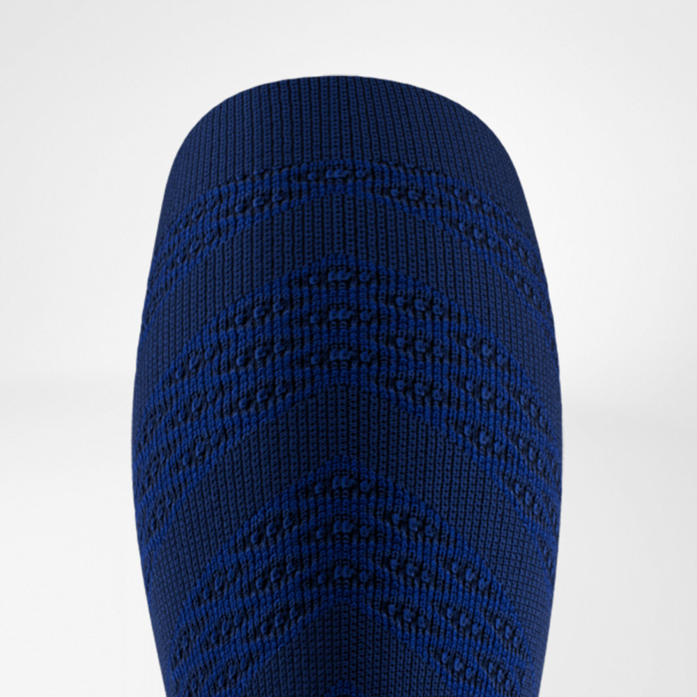 Dettaglio di una manica a compressione blu scuro con motivo a maglia a V. Il tessuto aderente evidenzia il design sportivo e il supporto funzionale per i muscoli del polpaccio.