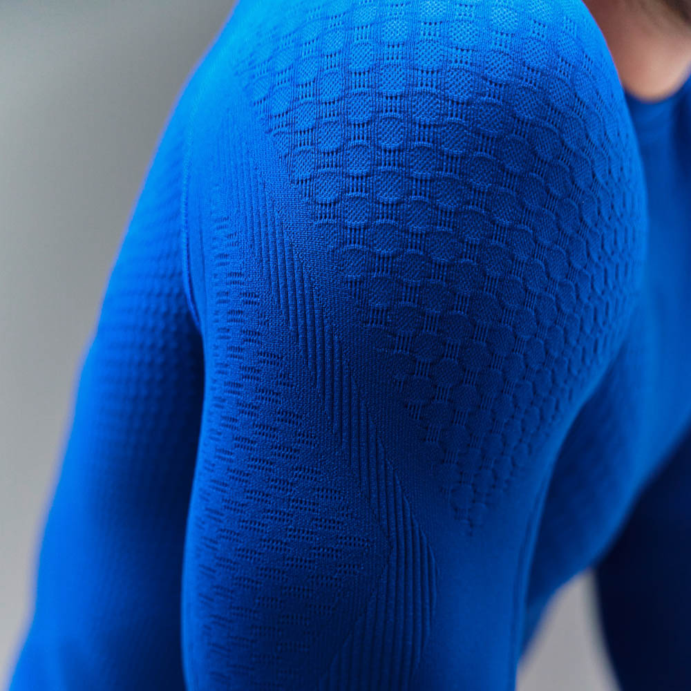 Top sportivo in maglia compressiva che enfatizza i muscoli Braccio superiore definito di un uomo che indossa un top compressivo blu a maniche lunghe