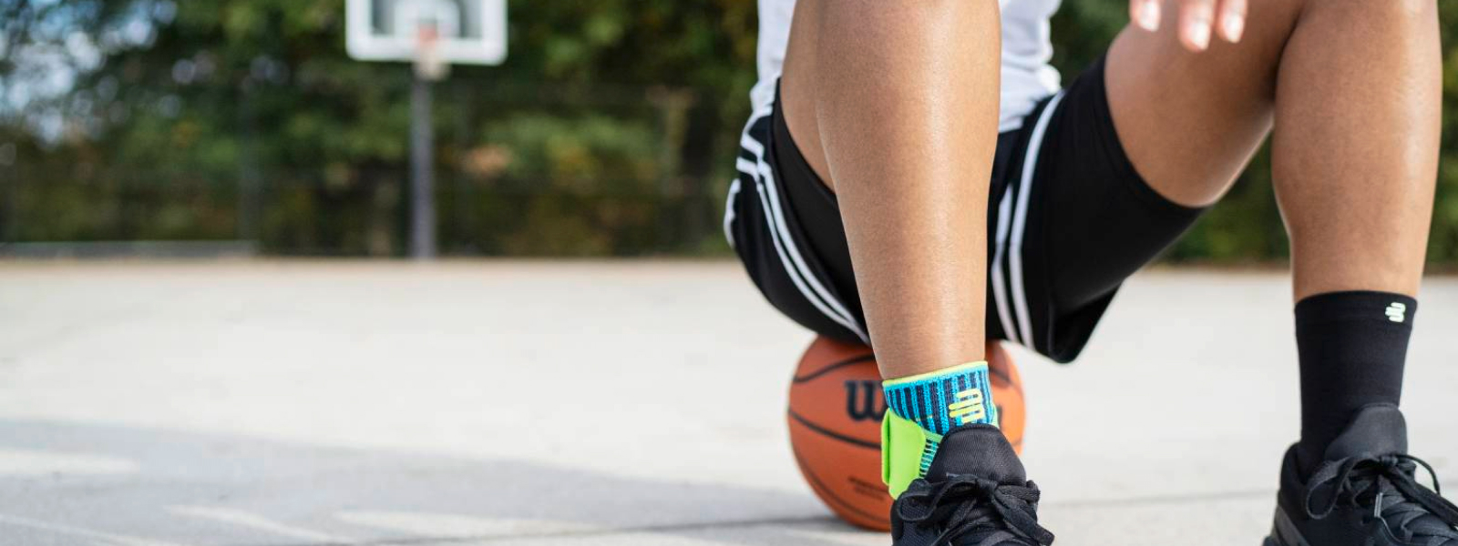 Il giocatore di streetball con bendaggio dei piedi si trova su un basket su un campo da strada