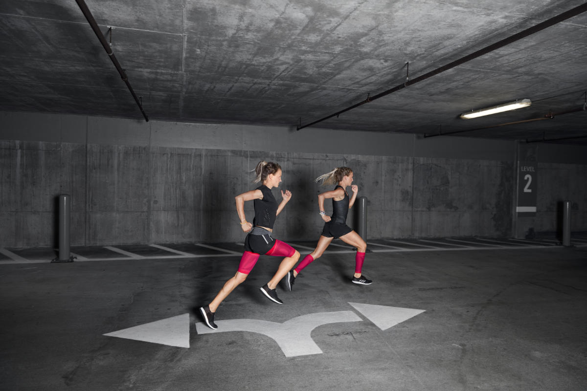 Due corridori con maniche a compressione rosa corrono attraverso un garage