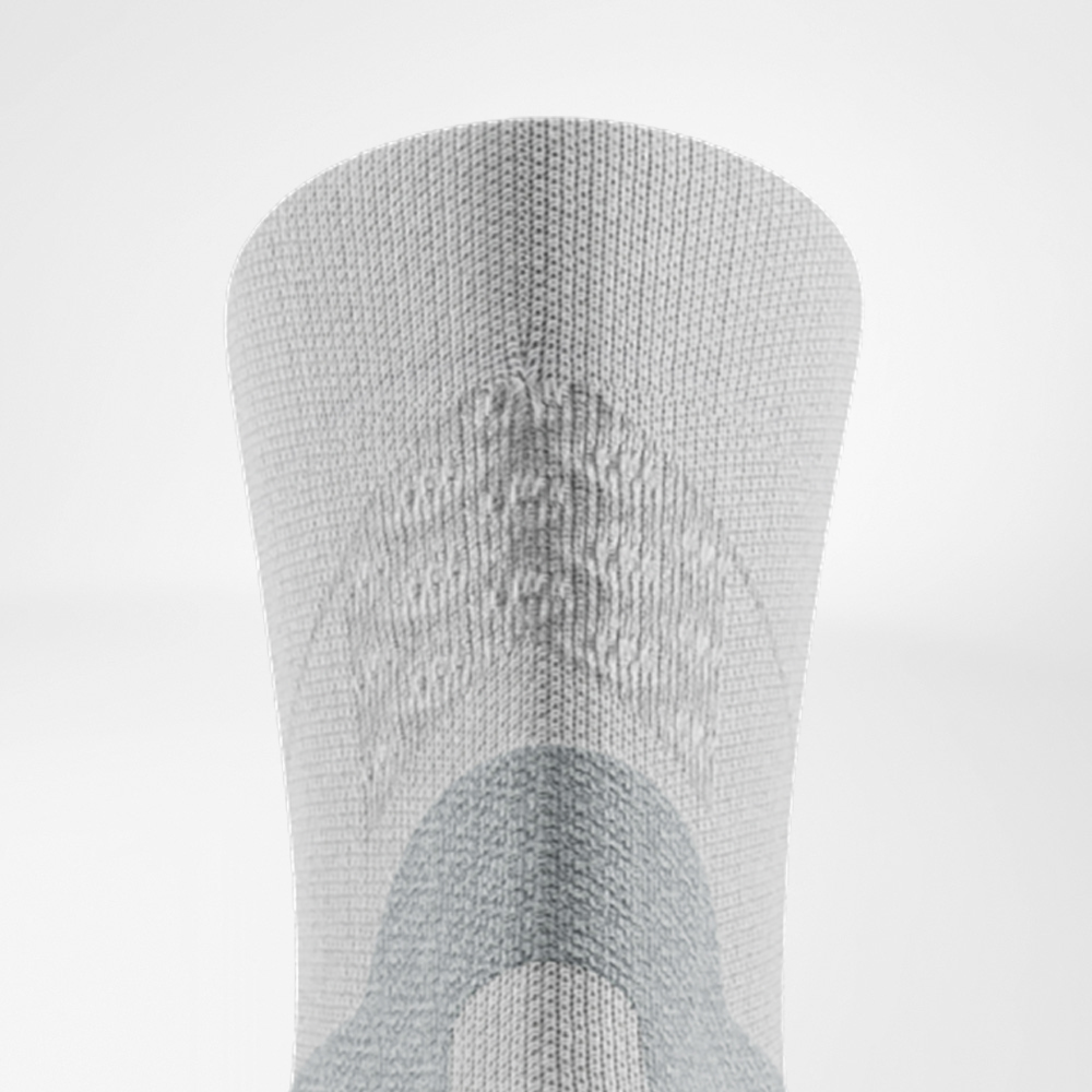 Dettaglio del retro della calza bianca Run Performance Midcut: zona comfort grigia per il tendine d’Achille, 3D dots lavorati a maglia sul bordo e zone di supporto lungo il polpaccio.