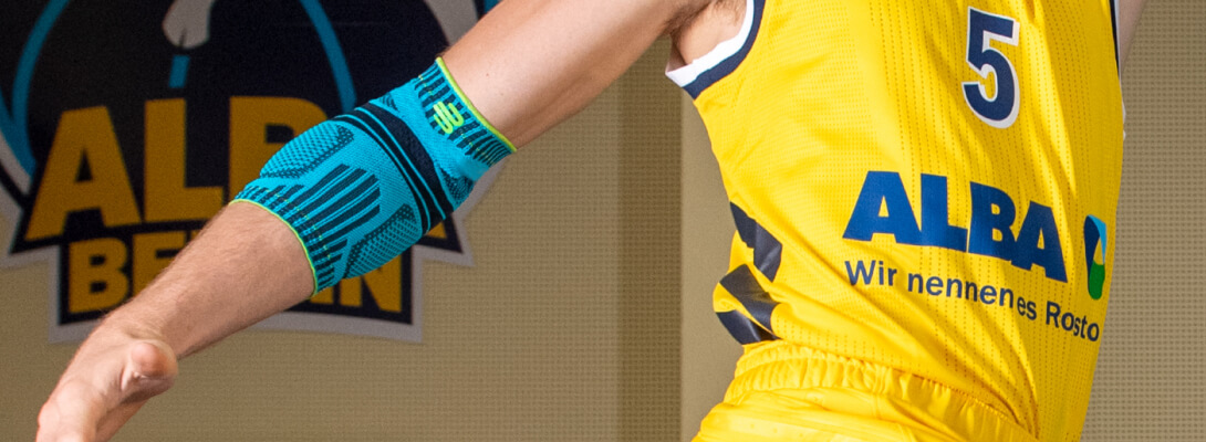 Il giocatore di basket con la maglia di Alba Berlin indossa una benda sportiva per il gomito