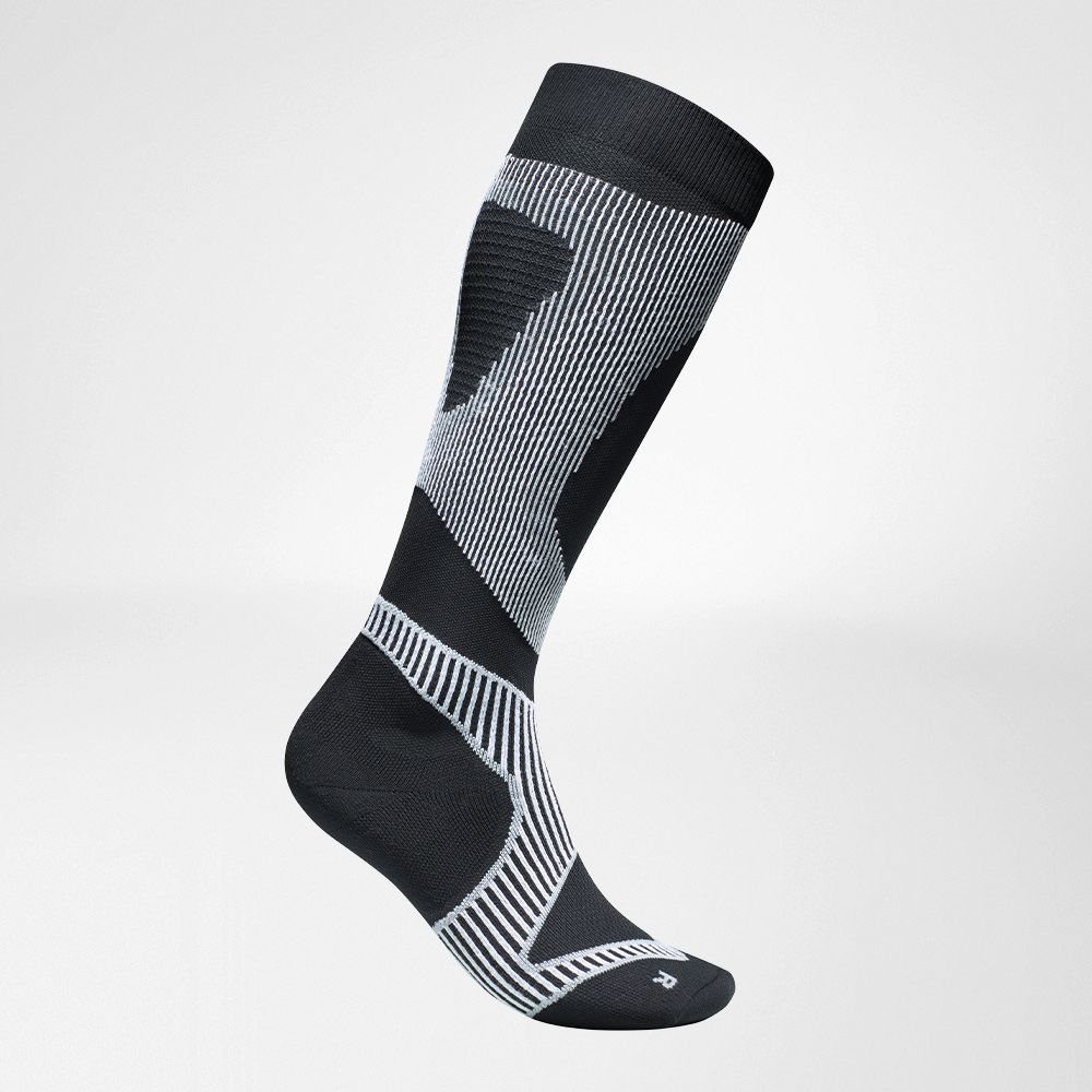 Vista completa laterale delle calze a compressione in bianco e nero da eseguire