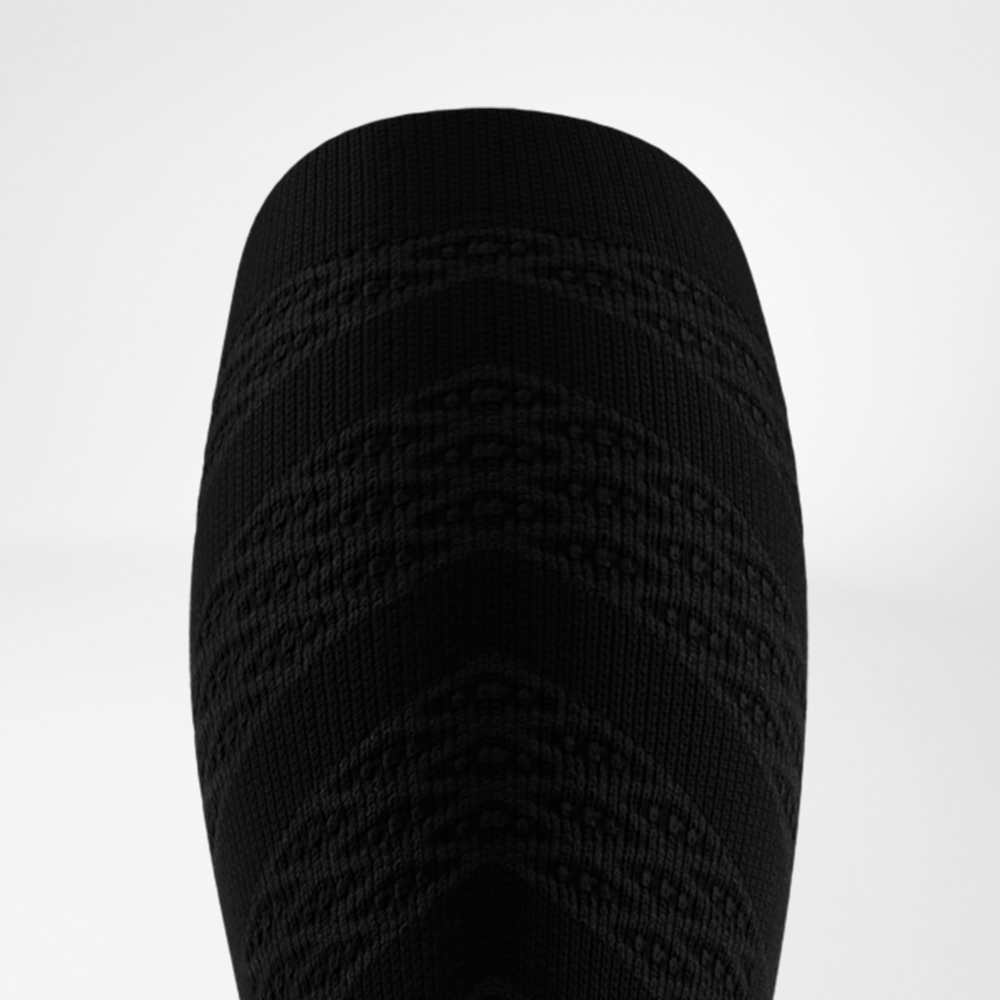 Vista dall’alto di una manica a compressione nera con motivo a zigzag. Stabilità e stile atletico in un design deciso.