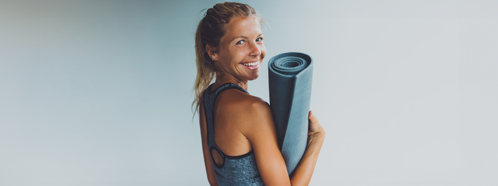 Lo yoga fa bene al corpo e alla mente Donna sorridente con un tappetino yoga