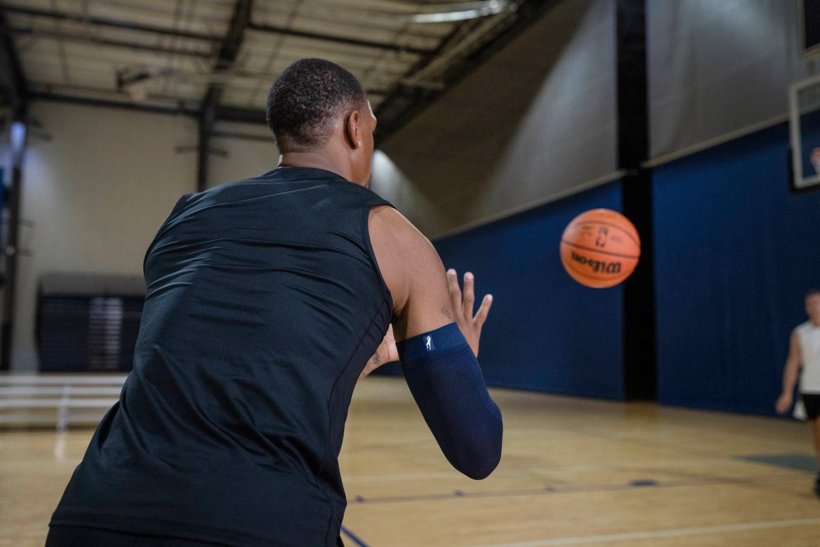 I giocatori di basket con un armatore blu nella sala sportiva attendono una palla che gli viene lanciata da un altro giocatore
