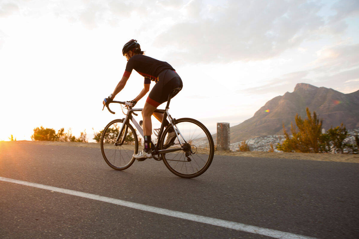 La donna corre su una bici da corsa su una strada verso il tramonto