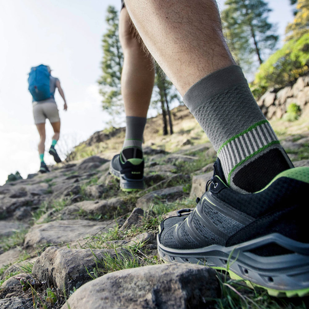 Escursionista con calze da trekking grigie che cammina su una montagna, zoom sulle calze