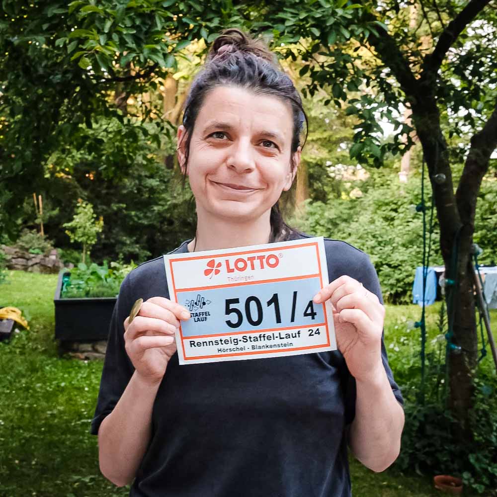 Targa di partenza per la Rennsteiglauf Una donna sorridente tiene in mano la targa della propria gara