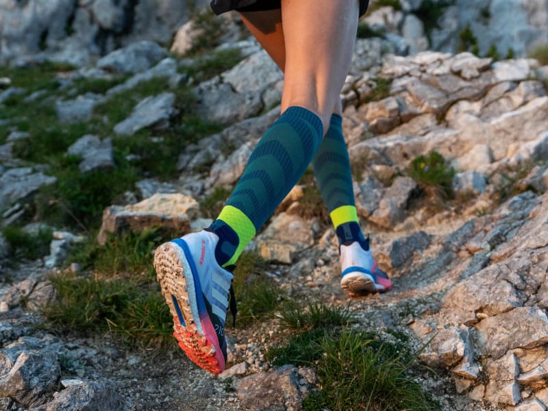 Il corridore corre in discesa pietrosa e indossa calzini da pista