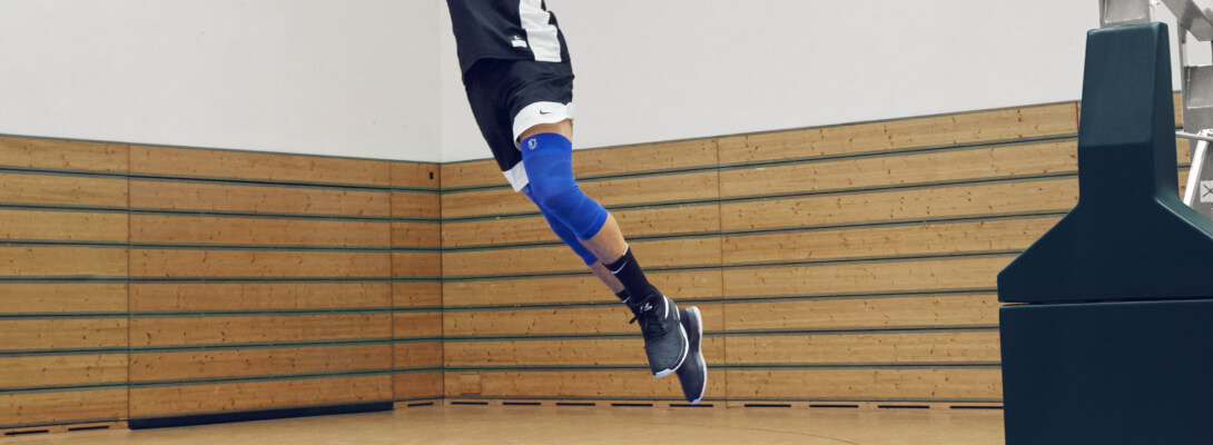 Il giocatore di base nel salto indossa una manica al ginocchio NBA