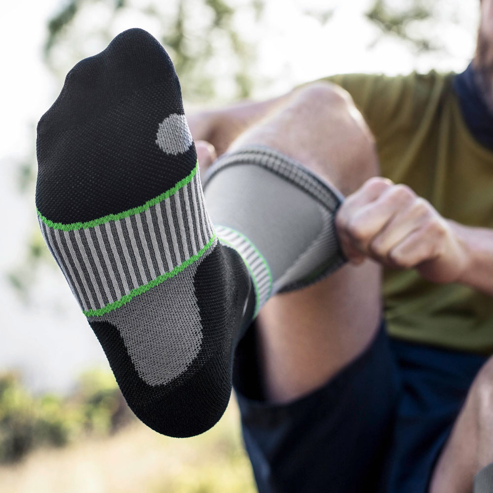 Zoom sulla parte inferiore del piede di un escursionista che indossa calze compressive grigie da trekking