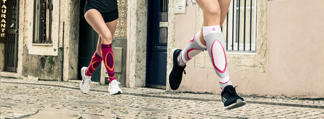 Corridore con calzini a compressione per la corsa che attraversa una città