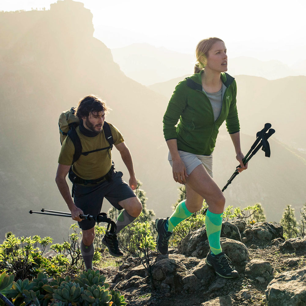 Due escursionisti I calzini a compressione per fare un'escursione corrono su una montagna