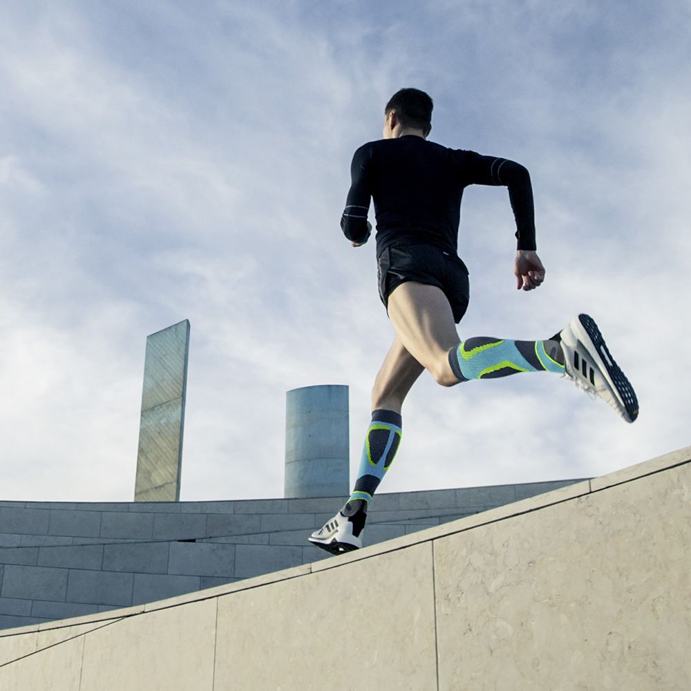 Corridore con calze a compressione per correre su un muro di pietra