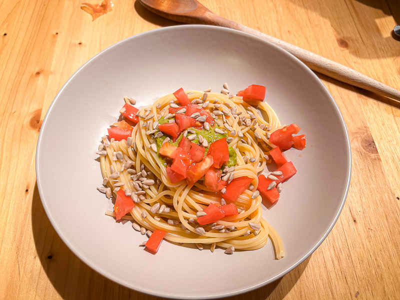 Pasta con pomodori e semi di girasole come fonte di carboidrati sani per il carbo-loading. Un piatto di spaghetti con pomodori freschi e semi di girasole, perfetto per un pasto ricco di carboidrati prima di una mezza maratona.