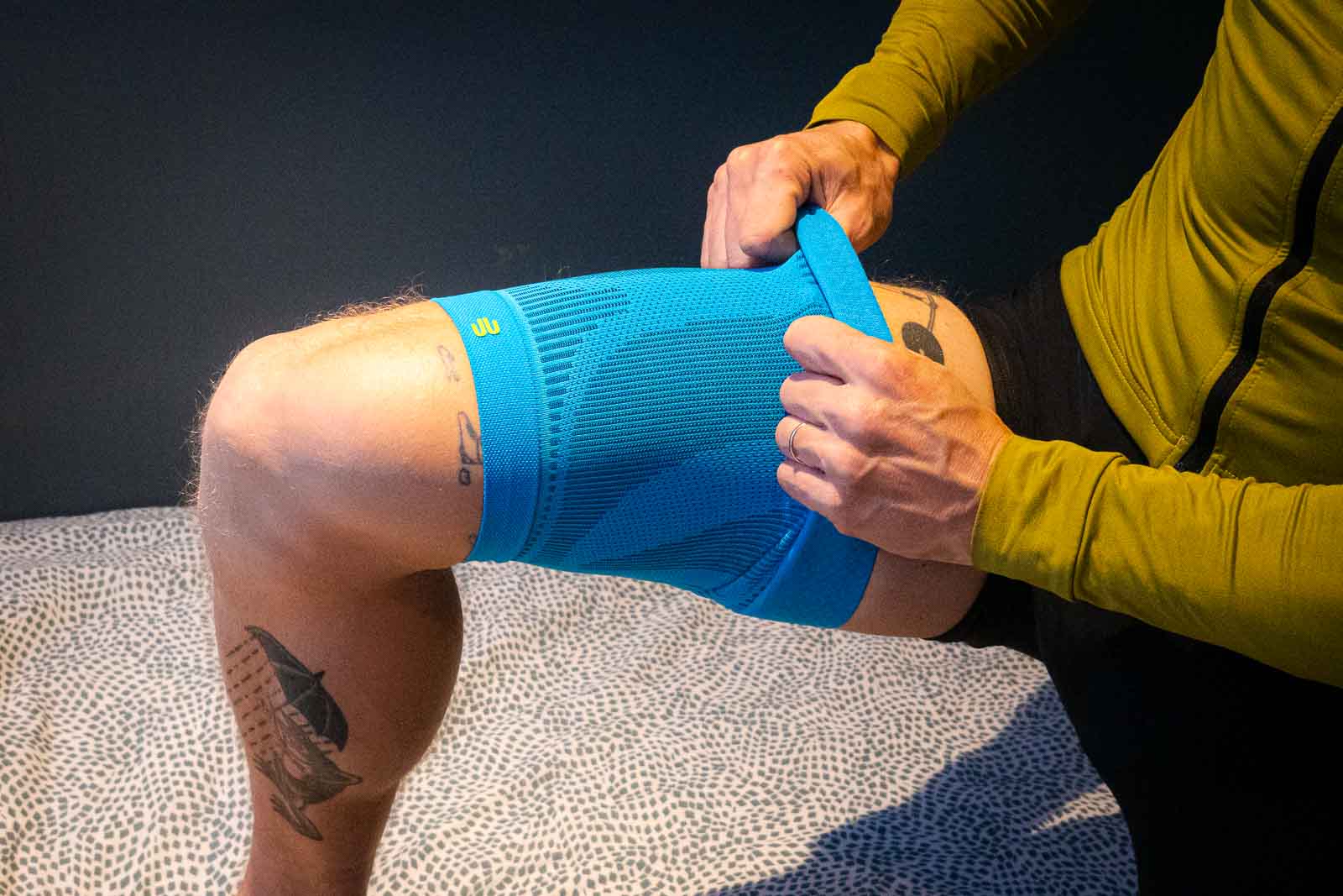 Un ciclista che indossa abbigliamento da ciclismo indossa una guaina compressiva blu sulla coscia.