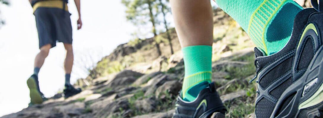 Escursionisti con calzini da trekking verdi corrono su una montagna, zoom sui calzini