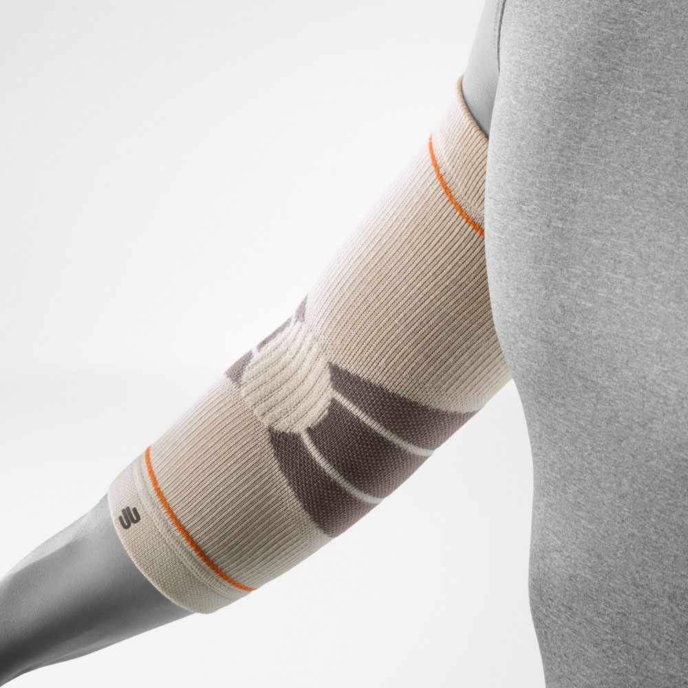 L’Outdoor Compression Elbow Support color sandstone è mostrato su un braccio piegato. La fascia aderisce al gomito e presenta una struttura a maglia studiata per offrire compressione mirata mantenendo libertà di movimento durante le escursioni.