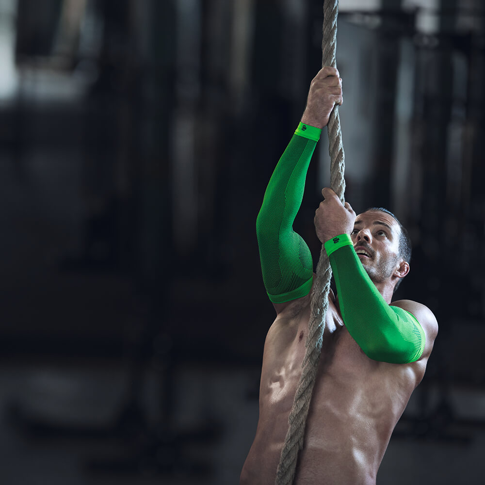 L'uomo che indossa un'arrampicata da corda indossa maniche a compressione verde per il braccio