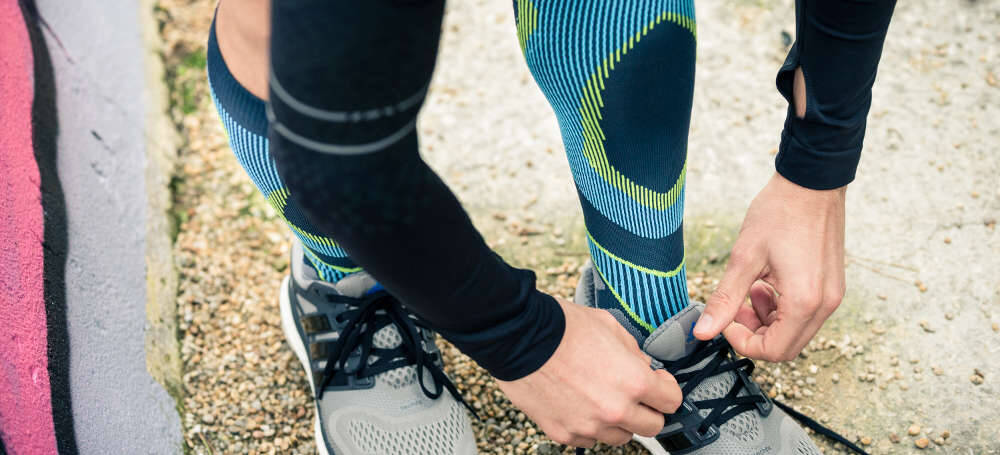 Uomo con calzini da corsa blu grigio allacciati le sue scarpe da corsa