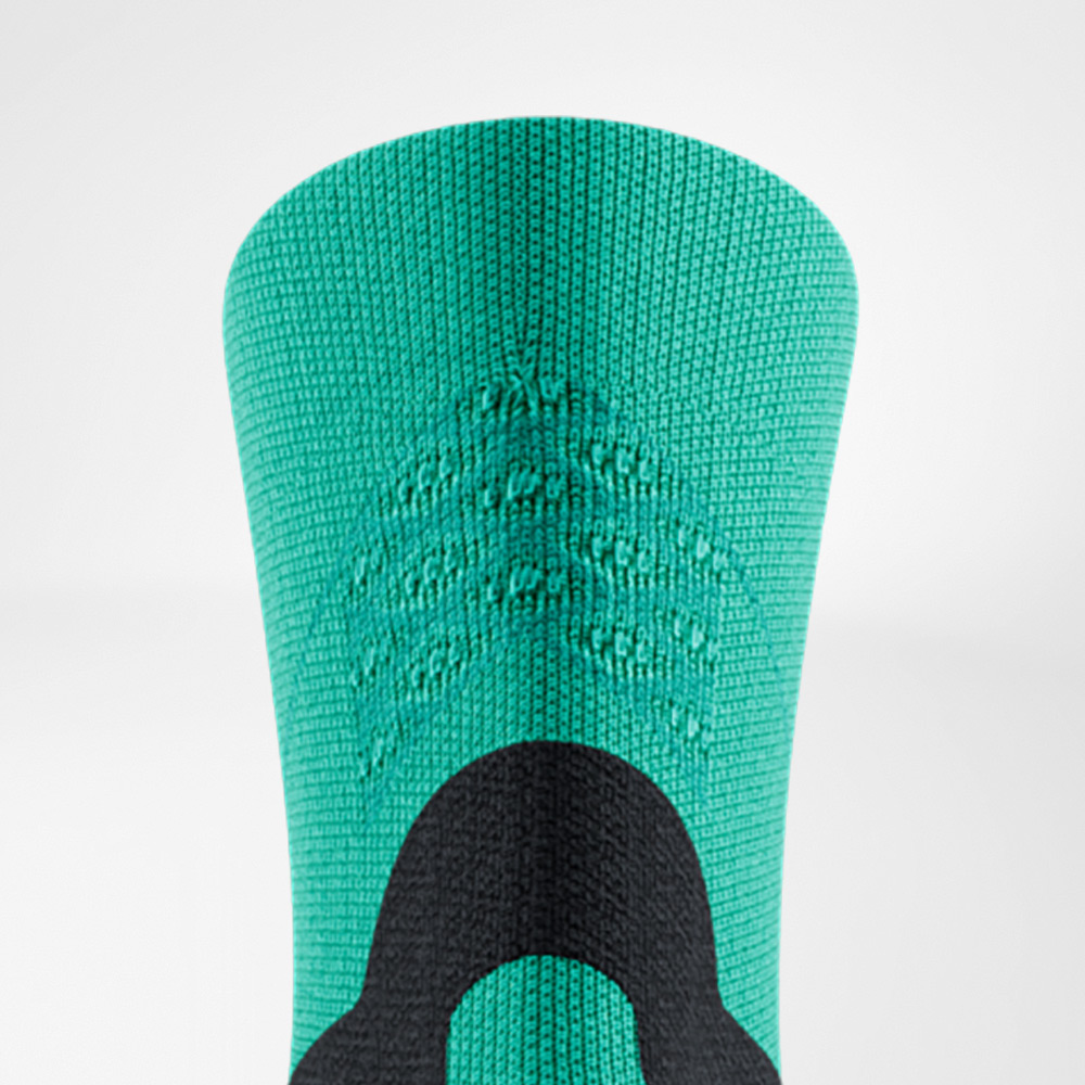 Dettaglio della parte superiore di una calza Run Performance Midcut verde di Bauerfeind. Sono chiaramente visibili le strutture tessute nella sezione superiore e un rinforzo nero che offre sostegno e stabilità.