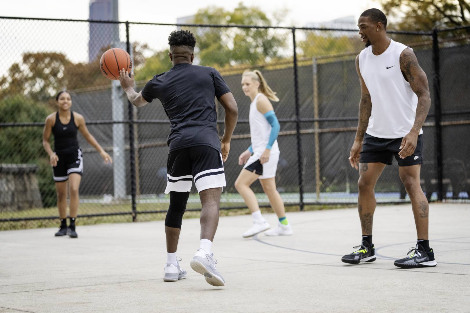 Quattro giocatori durante una partita di Street Ball dei giocatori in abbigliamento da gioco nero si adattano alla palla con il suo compagno di squadra