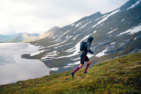 Trailrunner corre una montagna erbosa con il tempo piovoso