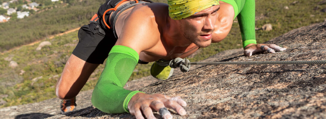 Arrampicata per manica a braccio Lo scalatore sulla roccia indossa maniche di compressione verde per il braccio
