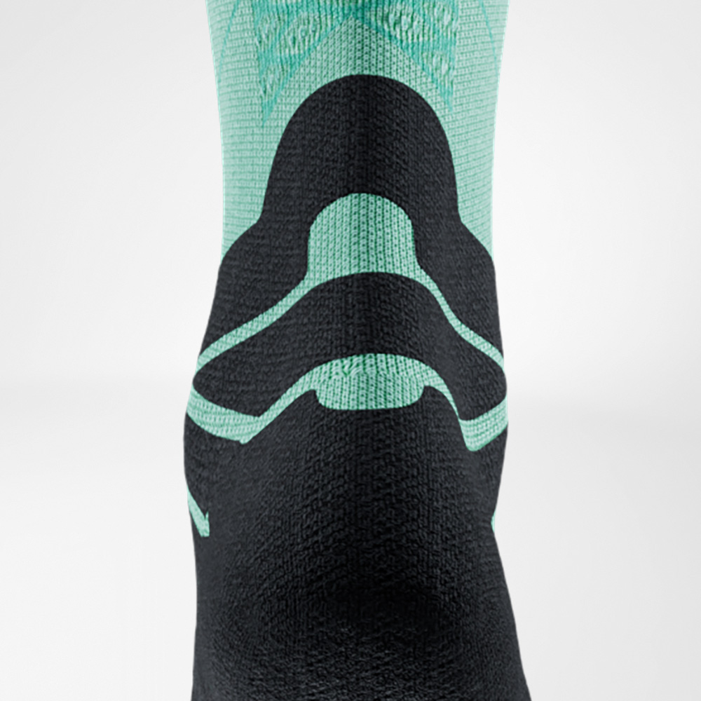 Vista posteriore di una calza da running verde e nera di Bauerfeind Sports, con focus sul tendine d’Achille. L’imbottitura speciale protegge durante l’attività sportiva.