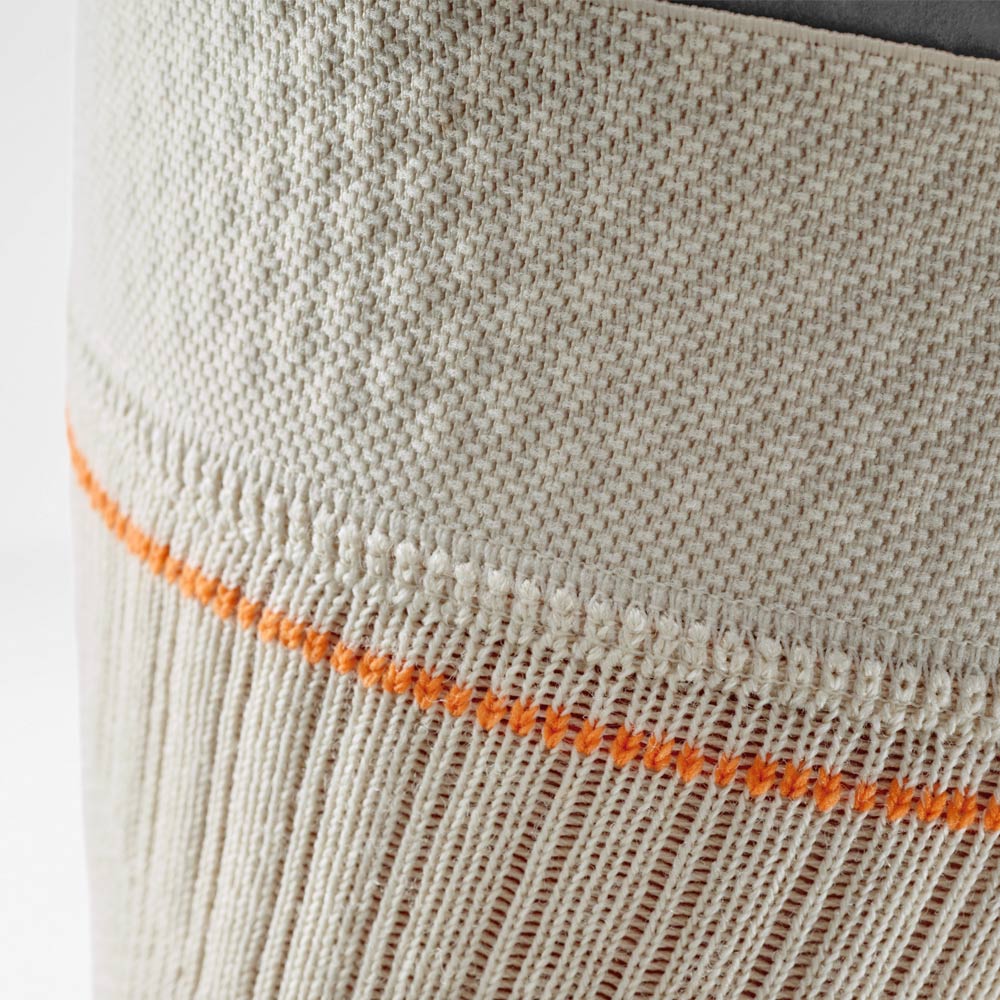 Dettaglio della ginocchiera color sabbia con cucitura a contrasto arancione. L’immagine mostra il tessuto a maglia traspirante sul bordo superiore che garantisce stabilità e comfort nelle attività outdoor.
