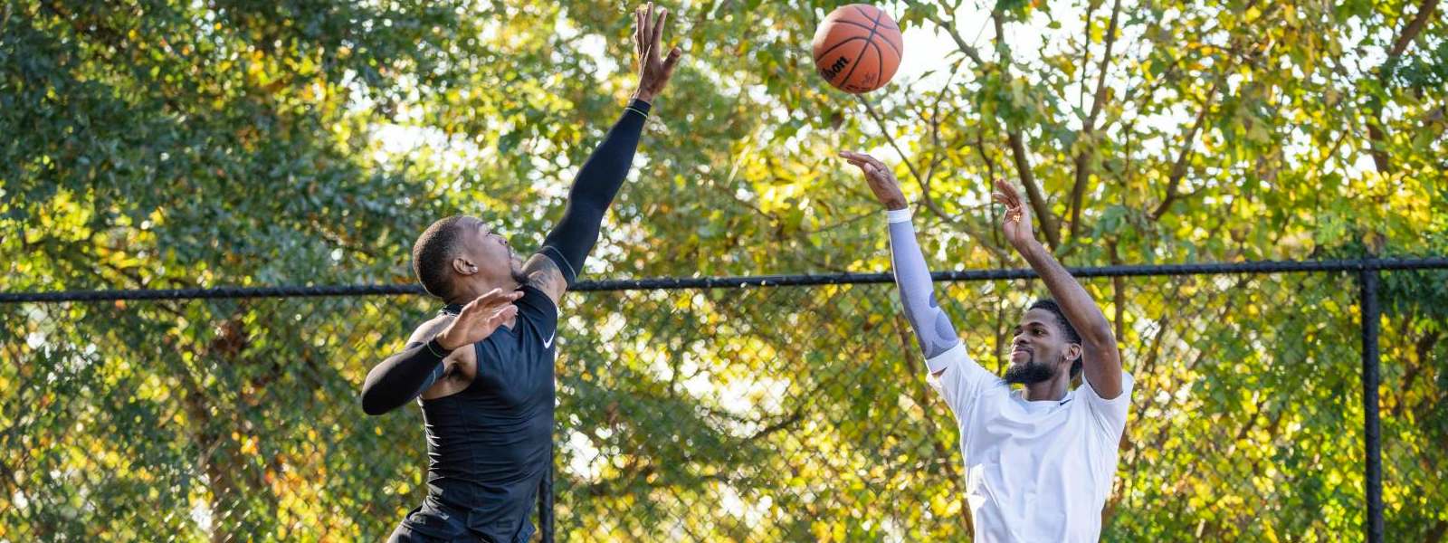 Spettacolare Air Action with Power: le nostre maniche e bende nel basket I giocatori di basket in abbigliamento da gioco nero cerca di bloccare il suo avversario in abiti bianchi in alto sopra il suolo