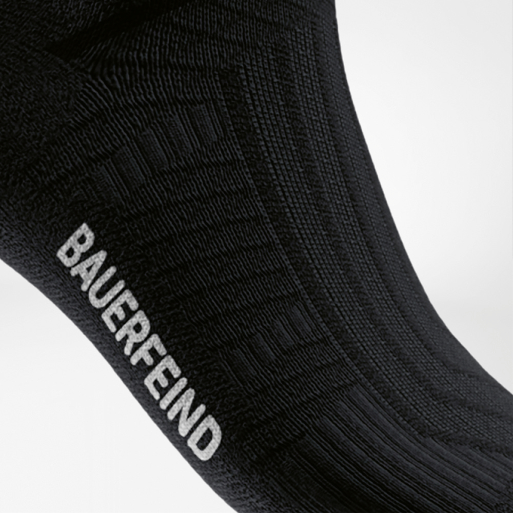 Dettaglio del collo del piede di una calza compressiva da corsa nera con logo BAUERFEIND integrato e struttura per una presa ottimale.