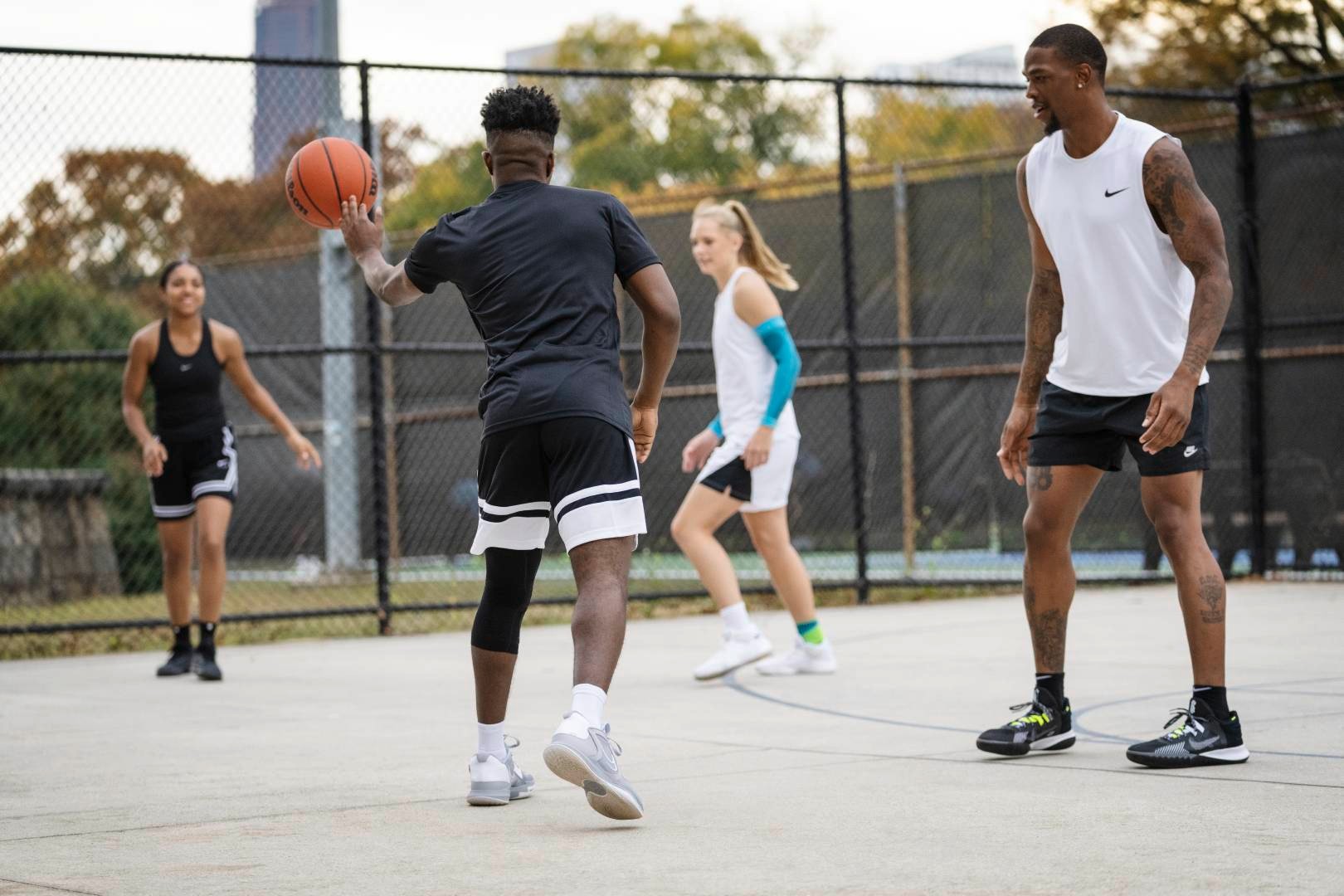 Quattro giocatori durante una partita di Street Ball dei giocatori in abbigliamento da gioco nero si adattano alla palla con il suo compagno di squadra