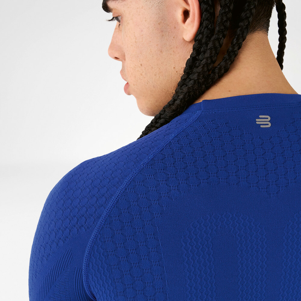 Vista posteriore di un atleta con una maglia a compressione blu con tessuto strutturato e capelli intrecciati.